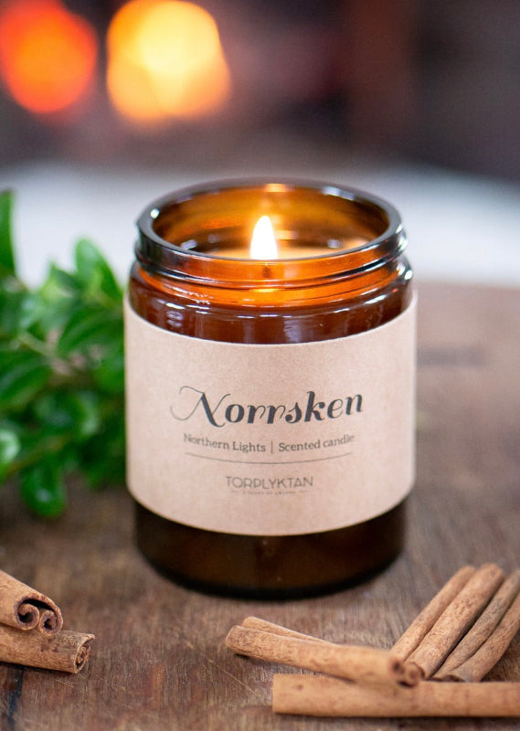Doftljus Norrsken med naturlig flamma i glas med kanelstänger bredvid